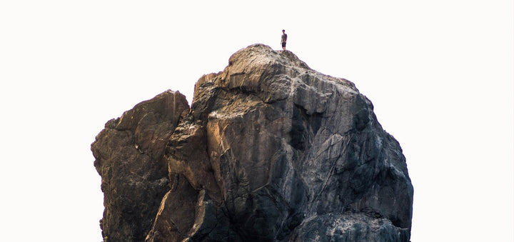 Einzelner Mann steht auf großem Felsen